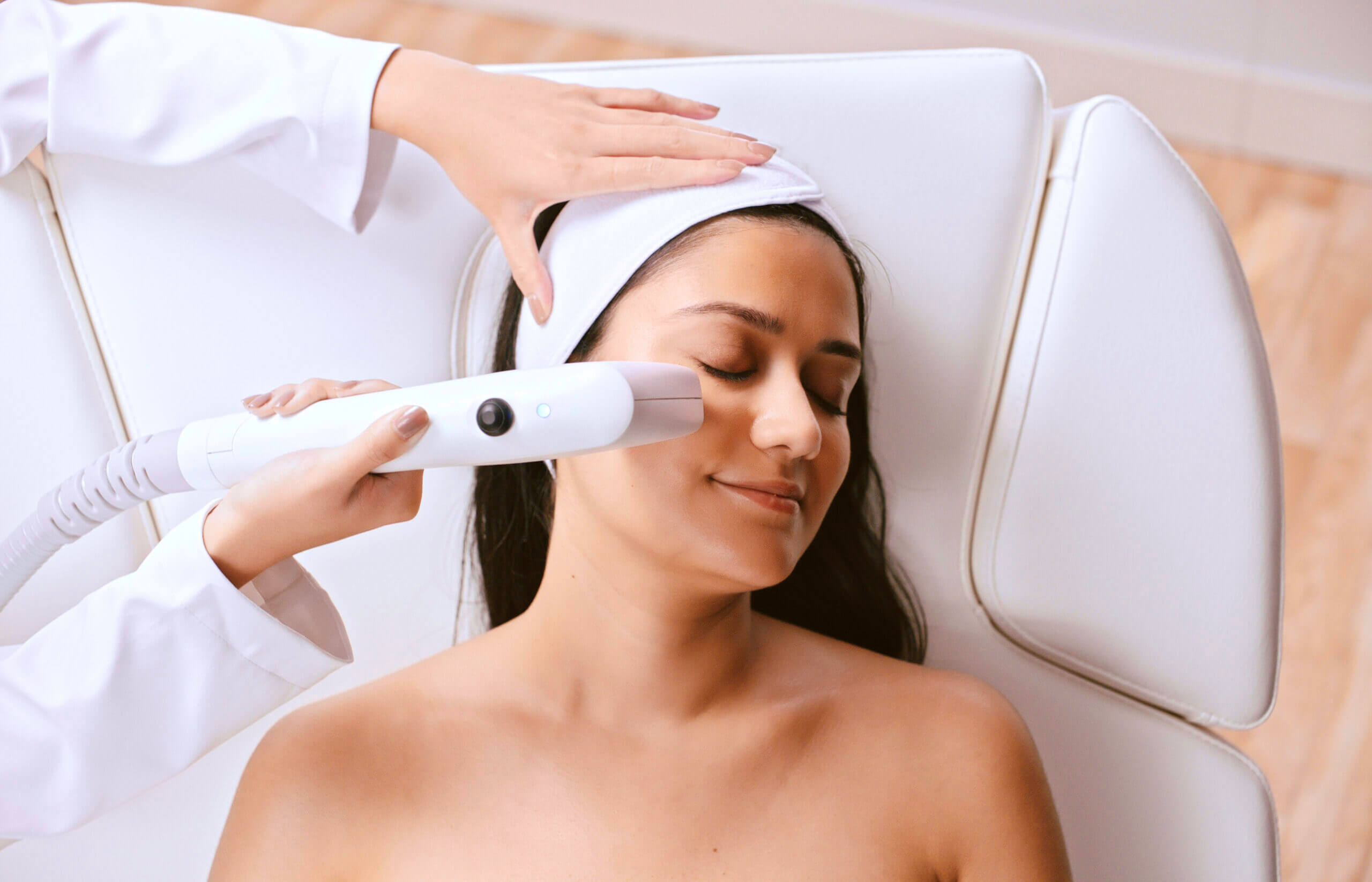 A Sofwave applicator delivering ultrasound to a client's face during treatment